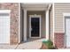View of front door with sidelight, garage, and brick veneer at 1916 Frost Dr, Haw River, NC 27258