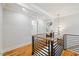 Hallway with wood railing and hardwood floors, with views of a modern light fixture and other rooms at 2605 Ridge Rd, Raleigh, NC 27612