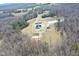 Aerial view of a property surrounded by a dense forest, featuring a house and multiple outbuildings at 3344 Cobb Farm Trl, Mebane, NC 27302