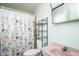 Compact bathroom featuring a pink sink and vanity, complemented by a floral shower curtain at 3344 Cobb Farm Trl, Mebane, NC 27302