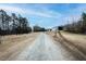 Long gravel driveway leading to the property, surrounded by trees and open fields at 3344 Cobb Farm Trl, Mebane, NC 27302