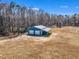 An aerial view captures a blue outbuilding with garage doors surrounded by trees and a pond at 3608 Buzzard Rd, Wendell, NC 27591