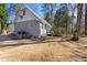 Exterior side view shows a cottage with metal roof, HVAC, and a small porch surrounded by trees at 365 Shawnee Dr, Louisburg, NC 27549