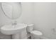 Bathroom featuring a pedestal sink, standard toilet, and a round mirror at 3727 Rosebush Dr, Zebulon, NC 27597