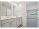 Bright bathroom featuring dual sinks, white cabinets, and a view into the bedroom at 3727 Rosebush Dr, Zebulon, NC 27597