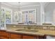 Close-up of kitchen with granite counter, sink, goose-neck faucet and breakfast bar with views through large picture windows at 4708 Wynneford Way, Raleigh, NC 27614
