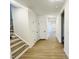 Well-lit hallway with wood-look flooring, featuring access to other rooms and a staircase leading to the upper level at 5161 Church Rd # 17, New Hill, NC 27562