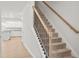 Carpeted staircase with wooden handrail leads to the upper level, adjacent to the modern kitchen with granite counters at 60 Commons Cir, Clayton, NC 27520