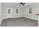 Bright living room featuring gray floors, white walls, three windows, and a white door at 915 E Holly St, Rocky Mount, NC 27801