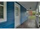 This is the side porch showing the wood plank flooring, the blue siding, and the white door at 915 E Holly St, Rocky Mount, NC 27801