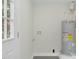 Utility room with a gray water heater, a window, gray floors and white walls at 915 E Holly St, Rocky Mount, NC 27801