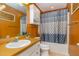 Inviting bathroom with orange walls, white vanity, toilet, and bathtub with blue patterned shower curtain at 1001 Strobus Ct, Wendell, NC 27591