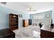 Bedroom with blue walls, large rug, ceiling fan, and ample storage with bookshelves and dressers at 10700 Chesson Dr, Raleigh, NC 27614