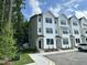Three-story townhome featuring white siding, black windows, and a well-maintained lawn at 1551 Crescent Townes Way, Raleigh, NC 27604