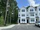 Modern white townhome with black-framed windows and doors, surrounded by lush greenery at 1551 Crescent Townes Way, Raleigh, NC 27604