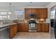Well-equipped kitchen featuring wooden cabinets, stainless steel appliances, and a cozy window view at 200 Indian Elm Ln, Cary, NC 27519