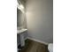 Cozy half-bathroom featuring a pedestal sink, round mirror, and wood-look flooring at 209 Deodora Ln, Cameron, NC 28326