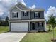 Charming two-story home featuring gray siding, black shutters, a white garage door, and a well-manicured lawn at 209 Deodora Ln, Cameron, NC 28326