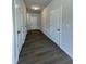 Hallway featuring wood-look floors, white doors, and neutral paint, offering access to various rooms at 209 Deodora Ln, Cameron, NC 28326