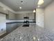 Well-lit kitchen featuring gray cabinets, granite countertops, and an island with a stainless steel sink at 209 Deodora Ln, Cameron, NC 28326