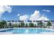 Community pool with lounge chairs in front of the townhome-style condos under a blue sky with white fluffy clouds at 2325 Ballywater Lea Way, Wake Forest, NC 27587