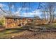 Brick home's backyard featuring a large deck, mature trees, and a well-maintained lawn at 2409 Parkway Dr, Raleigh, NC 27603