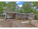 Charming single-story brick home with light blue shutters, mature trees, and a covered carport with brick accent wall at 2409 Parkway Dr, Raleigh, NC 27603