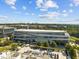 Aerial view of a modern gray commercial building with parking, greenery, and a distant skyline at 2441 Campus Shore # 402, Raleigh, NC 27606