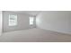 Large, bright bedroom showcasing neutral walls, carpet flooring, and two windows at 261 Hawksmoore Ln, Lillington, NC 27546