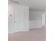 Hallway with white walls, baseboards, and carpeted floors, featuring a closed door and a view of another room at 261 Hawksmoore Ln, Lillington, NC 27546