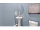 Powder room featuring blue walls, modern mirror, pedestal sink, and commode at 269 Hawksmoore Ln, Lillington, NC 27546