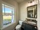This powder room features a granite vanity, a toilet, and a large window looking out into the front yard at 377 Earnest Way, Kenly, NC 27542