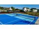 Bright blue tennis court with net, surrounded by fencing and houses in the background at 44 Blue Iris Pkwy # 121, Clayton, NC 27520