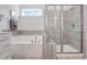 Bright bathroom featuring a tiled shower, soaking tub, modern fixtures and a bright window at 625 Emerald Bay Cir, Raleigh, NC 27610
