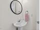 Bathroom with a sleek pedestal sink, a round mirror and a decorative towel at 6534 Rossford Ln, Durham, NC 27713