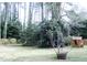 A lush backyard featuring tall trees, greenery, and a quaint playhouse nestled among the foliage at 711 Stuart Dr, Sanford, NC 27330