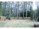The serene backyard has a wooded area, with a fire pit, and fenced in area for gardening or play at 711 Stuart Dr, Sanford, NC 27330