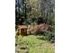 A quaint backyard playhouse is nestled among colorful azaleas, and lush green foliage at 711 Stuart Dr, Sanford, NC 27330