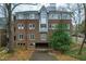 Multi-story brick condo building with light gray trim surrounded by lush greenery and trees at 741 Bishops Park Dr # 204, Raleigh, NC 27605