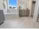 A bright bathroom showcasing a soaking tub, vanity with grey cabinets, and marble flooring at 812 Emerald Bay Cir, Raleigh, NC 27610