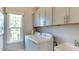 Bright laundry room features gray cabinets, white washer and dryer, and a window for natural light at 840 Emerald Bay Cir, Raleigh, NC 27610