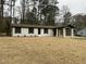Renovated brick house with black shutters and covered entrance, surrounded by mature trees and natural landscaping at 905 Spruce Pine Trl, Durham, NC 27705