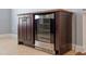 Close up of a wine fridge with wooden cabinetry, stainless steel trim, and storage shelves at 10321 Sablewood Dr # 108, Raleigh, NC 27617