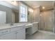 Bright bathroom with dual sinks, white cabinets, quartz countertops, and a glass-enclosed shower at 104 Bearwallow Forest Way, Wendell, NC 27591