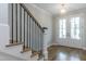 Inviting foyer featuring a staircase with iron railings, hardwood floors, and a bright double-door entrance at 104 Bearwallow Forest Way, Wendell, NC 27591