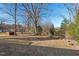 Large backyard featuring mature trees, wooden stumps, and a storage shed at 1204 Donphil Rd, Durham, NC 27712