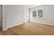 Empty bedroom with hardwood floors, white walls, double door closet, and a large window at 1204 Donphil Rd, Durham, NC 27712