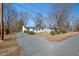 Charming one-story home featuring a gravel driveway, mature trees, manicured shrubs, and a classic design at 1204 Donphil Rd, Durham, NC 27712