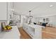 Modern white kitchen with a large island, quartz countertops, and stainless steel appliances opens to living room at 1204 Donphil Rd, Durham, NC 27712