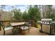Wooden deck with a dining set and a stainless steel barbeque and a treed backdrop at 1226 Woodland Church Rd, Wake Forest, NC 27587